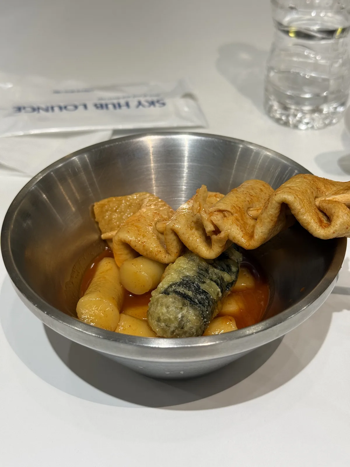 SkyHub Lounge snack corner with tteokbokki, dumplings, and cup noodles