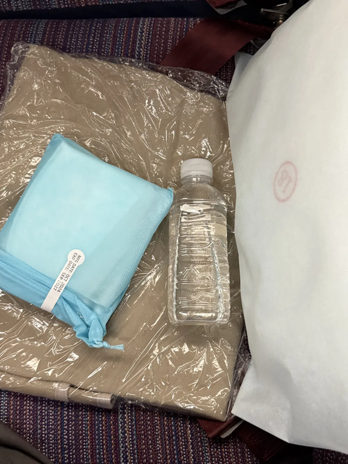 Korean Air economy class seat amenities including pillow, blanket, and pouch with socks and toothbrush
