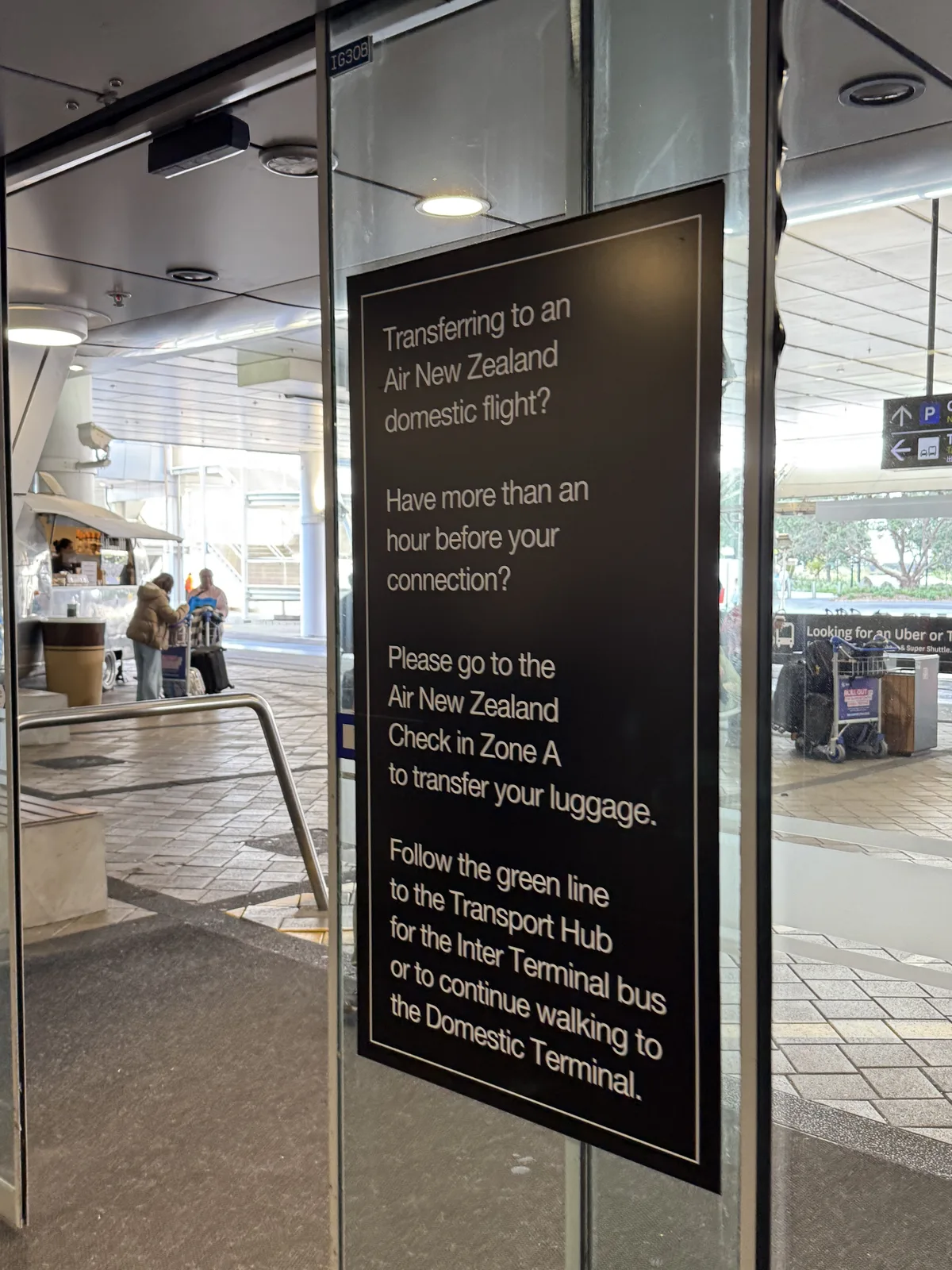 Directional signage at Auckland Airport pointing to domestic terminal transfer