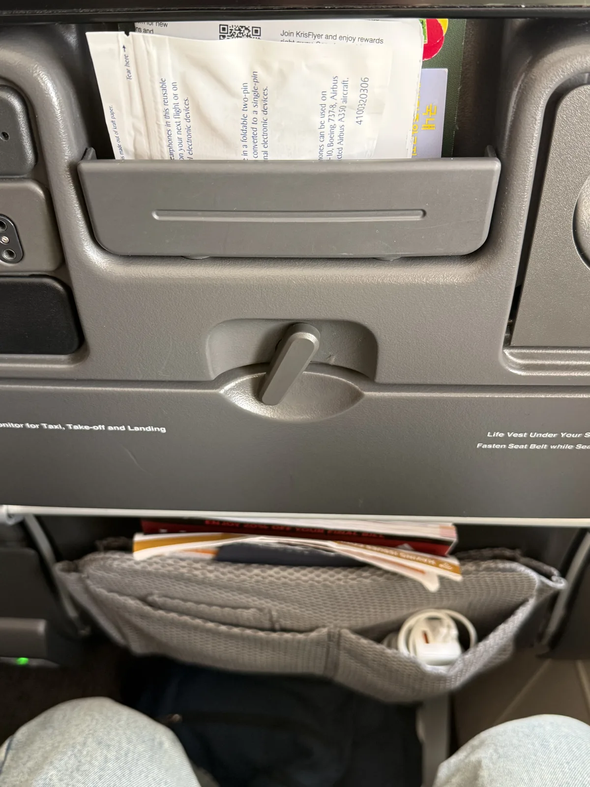 Singapore Airlines economy seat storage area and shared power outlet underneath