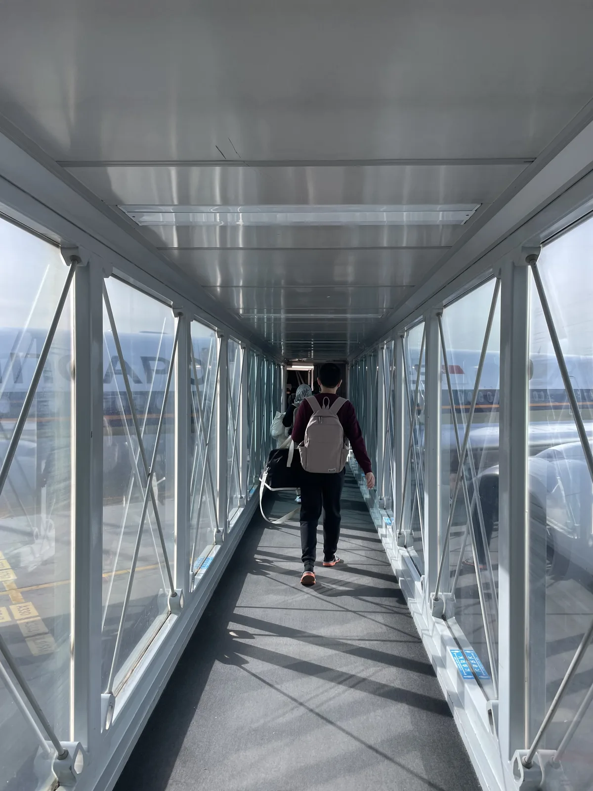 Glass-walled jet bridge at Incheon Airport offering views of Singapore Airlines A350