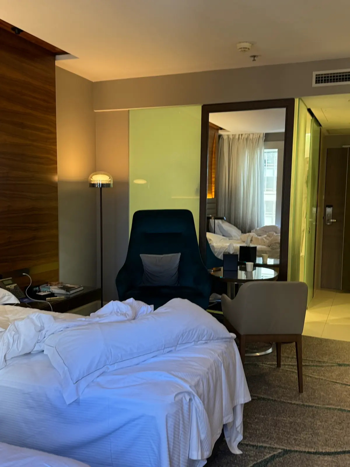 Hilton Sydney twin room interior showing bathroom entrance, minibar, chairs, and two beds