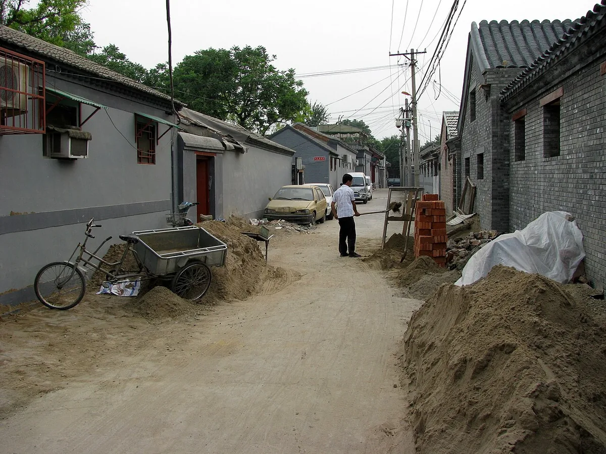 Grey brick houses in a Beijing hutong with a bicycle and cart