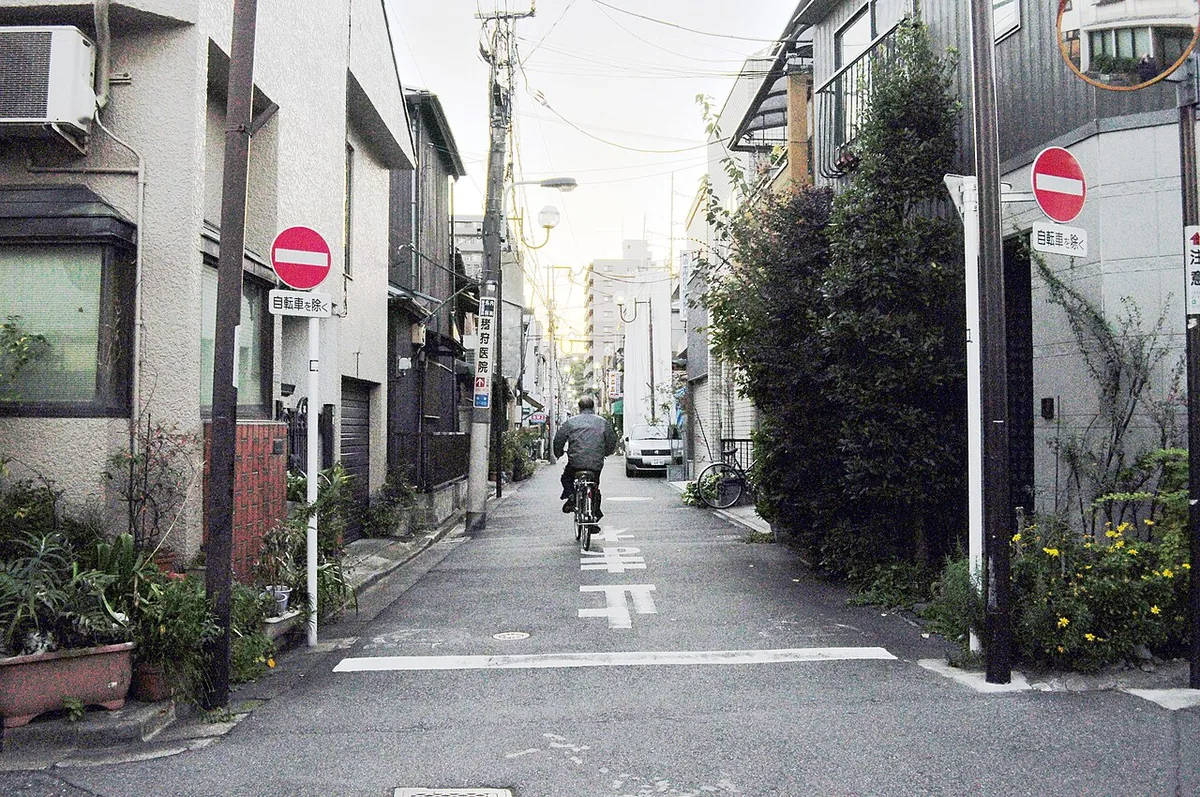 Narrow residential street in Yanaka, Tokyo, with a cyclist