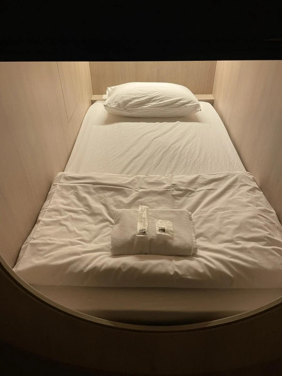 흰 침구와 수건이 놓인 1층 캡슐 침대