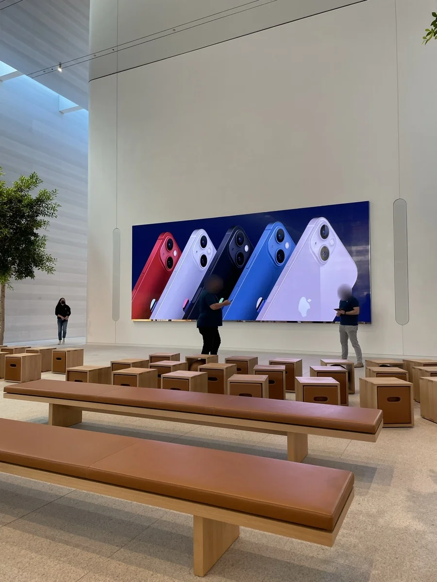 대형 비디오 월과 원목 큐브 좌석이 배치된 Today at Apple 세션 공간